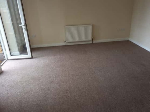 This is a photo of a living room after it has been cleaned. The room is empty and has a brown carpet that has been steam cleaned works carried out by Penge Carpet Cleaning