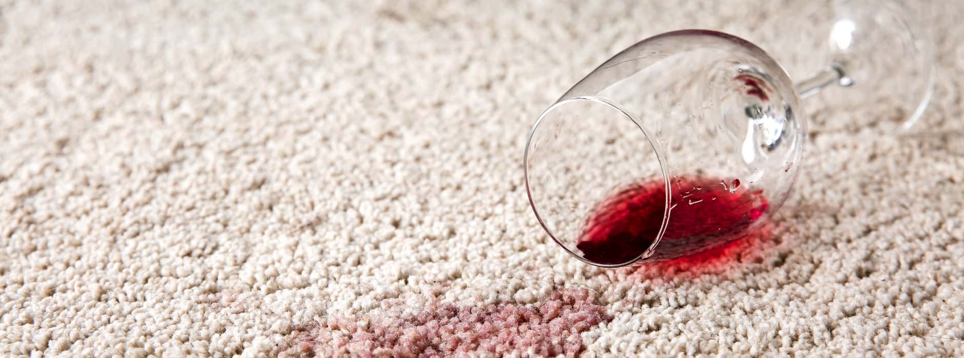 This is a photo of red wine which has been spilt on a cream carpet. The glass is on its side.